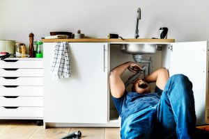 A plumber works on sink
