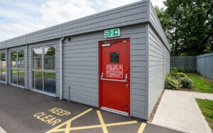 clearly marked fire exit door and emergency signage on the exterior of a prefab school building