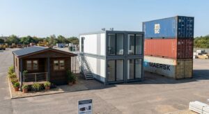 showing a single-story cabin, a stacked office block, and a container stack side by side]