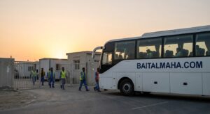 Company bus collecting workers from a labour camp in Sharjah Industrial Area at sunrise