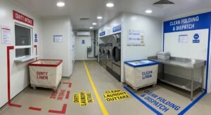 Interior of a laundry cabin for labour camps with marked clean and dirty laundry zones and trolleys
